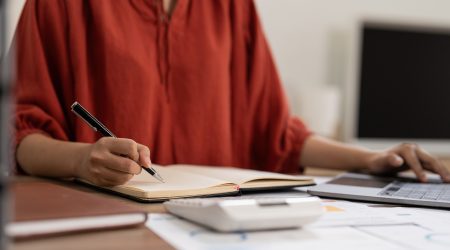 Asian Business woman writing saving account balance with working at home, account and saving concept